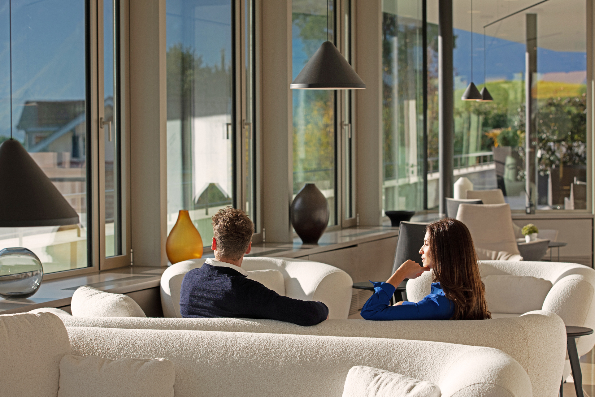 Couple relaxing on white sofas in a sunlit wellness lounge